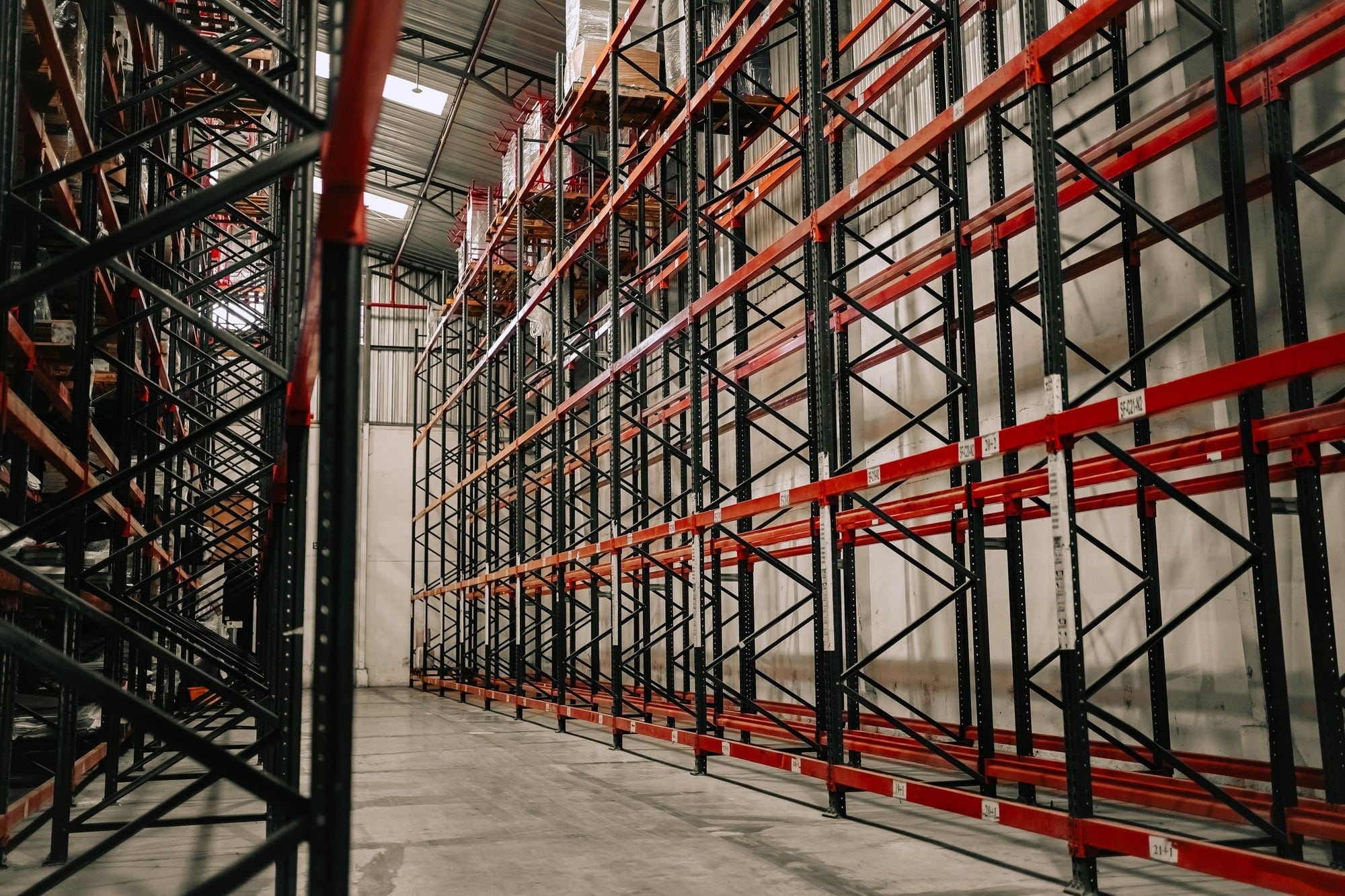 Corsia pulita tra scaffalature industriali con pavimento in primo piano